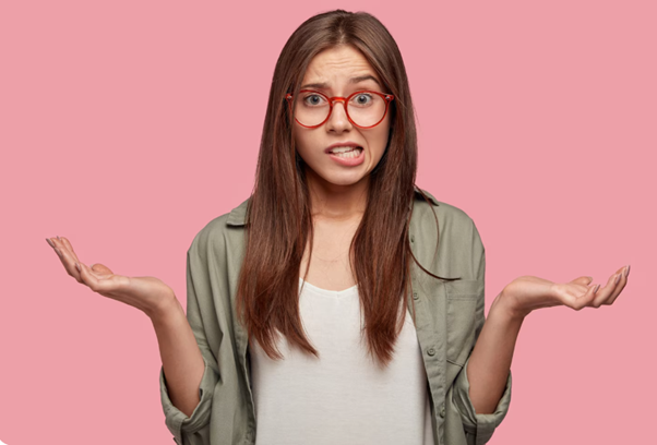 Young woman with red glasses shrugging with a puzzled expression against a pink backdrop.