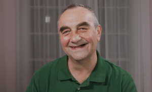 Smiling man in a green polo shirt posing indoors against a neutral background.